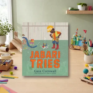 Long Childhood - A children’s book titled “Jabari Tries” by Gaia Cornwall is displayed upright on a wooden desk with art supplies and toys in the background.