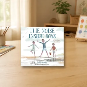 Long Childhood - Children’s book titled “The Noise Inside Boys” by Pete Oswald is displayed on a wooden table, with a blurred home interior in the background.